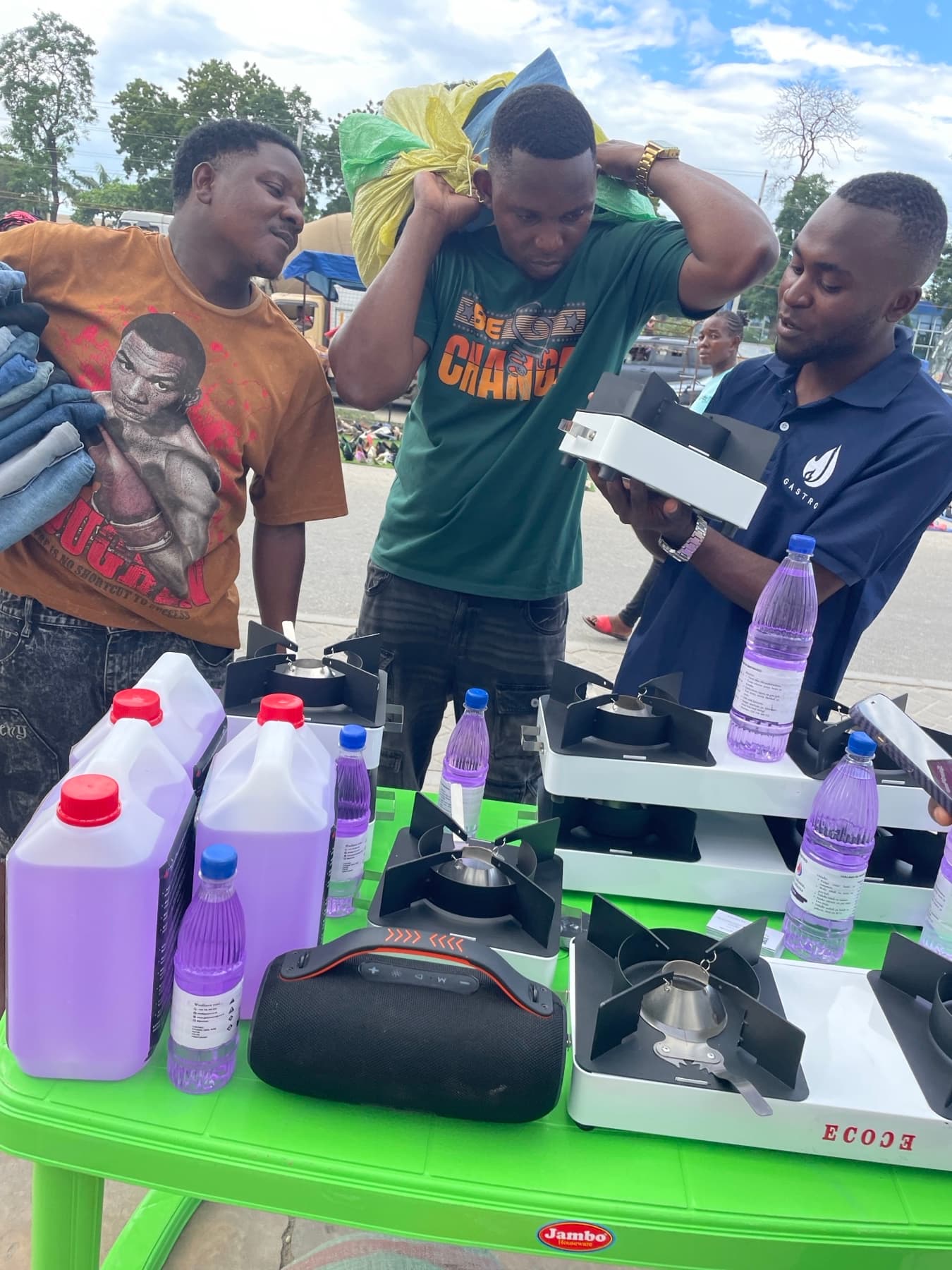 A Gastro team member showing ethanol cookstoves and fuel bottles to customers at a market demonstration