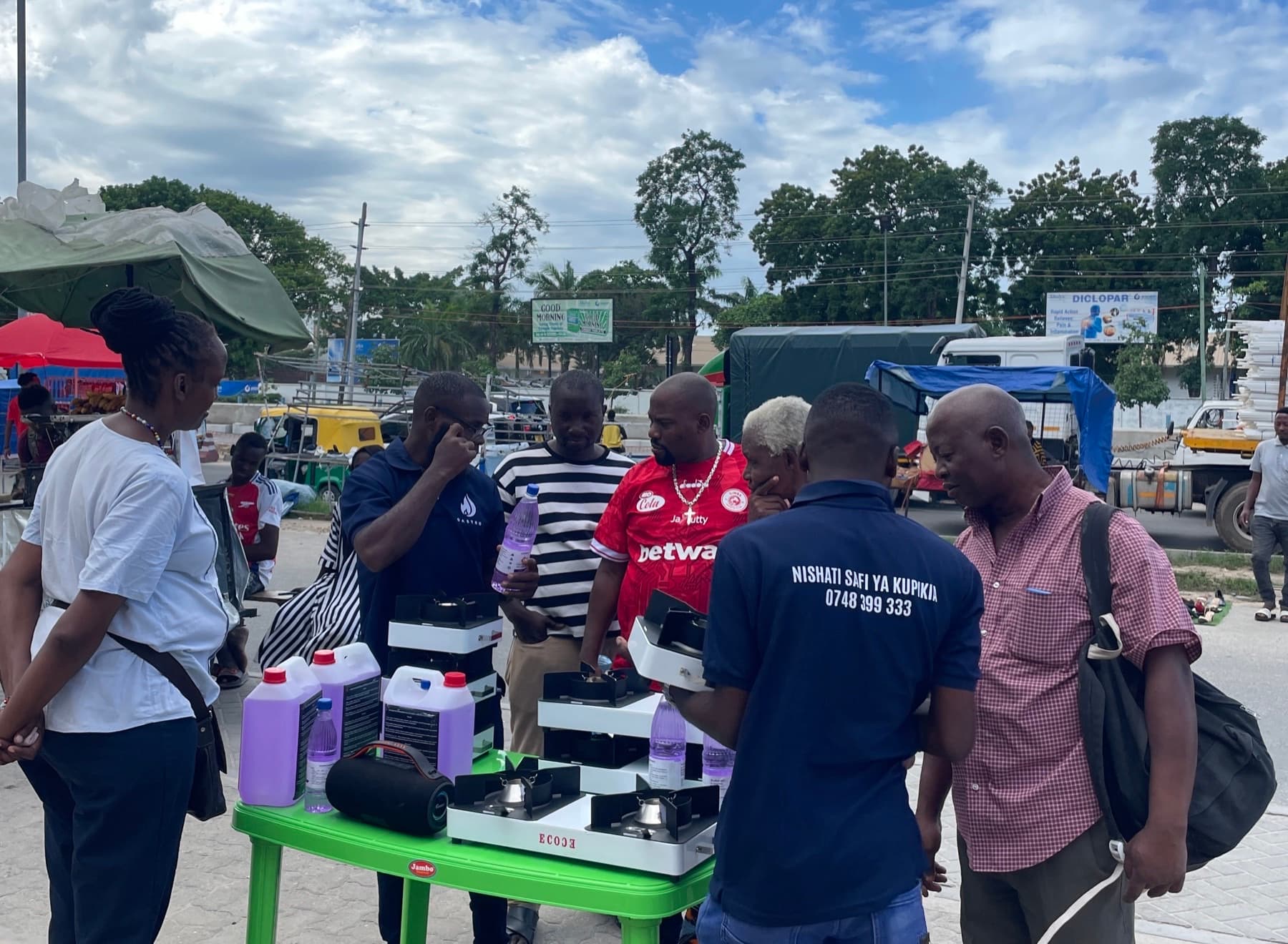 Gastro team members showing cookstoves and ethanol fuel to customers gathered around a market display table